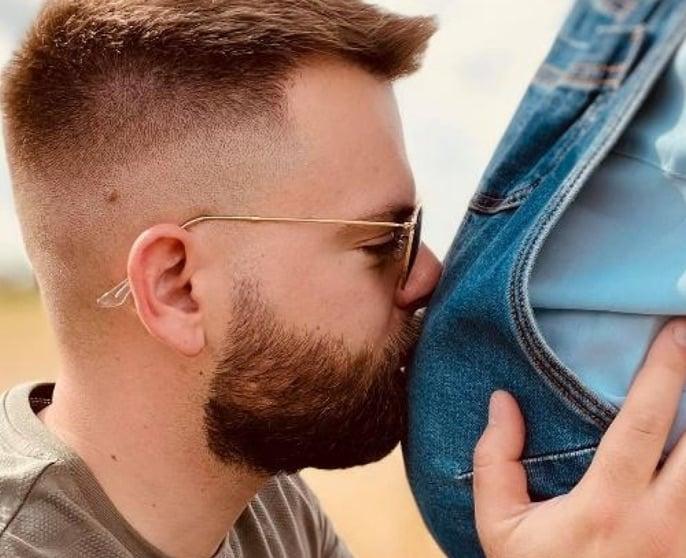 Christopher küsst den Bauch der schwangeren Marine.